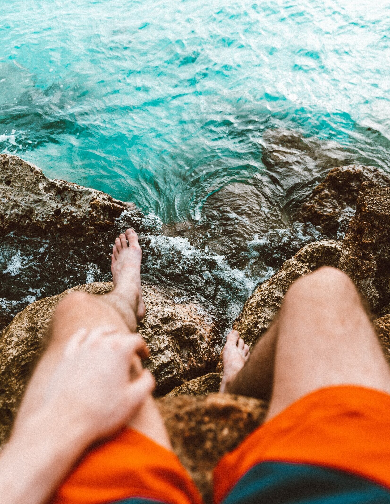 person sitting on rocks by ocean